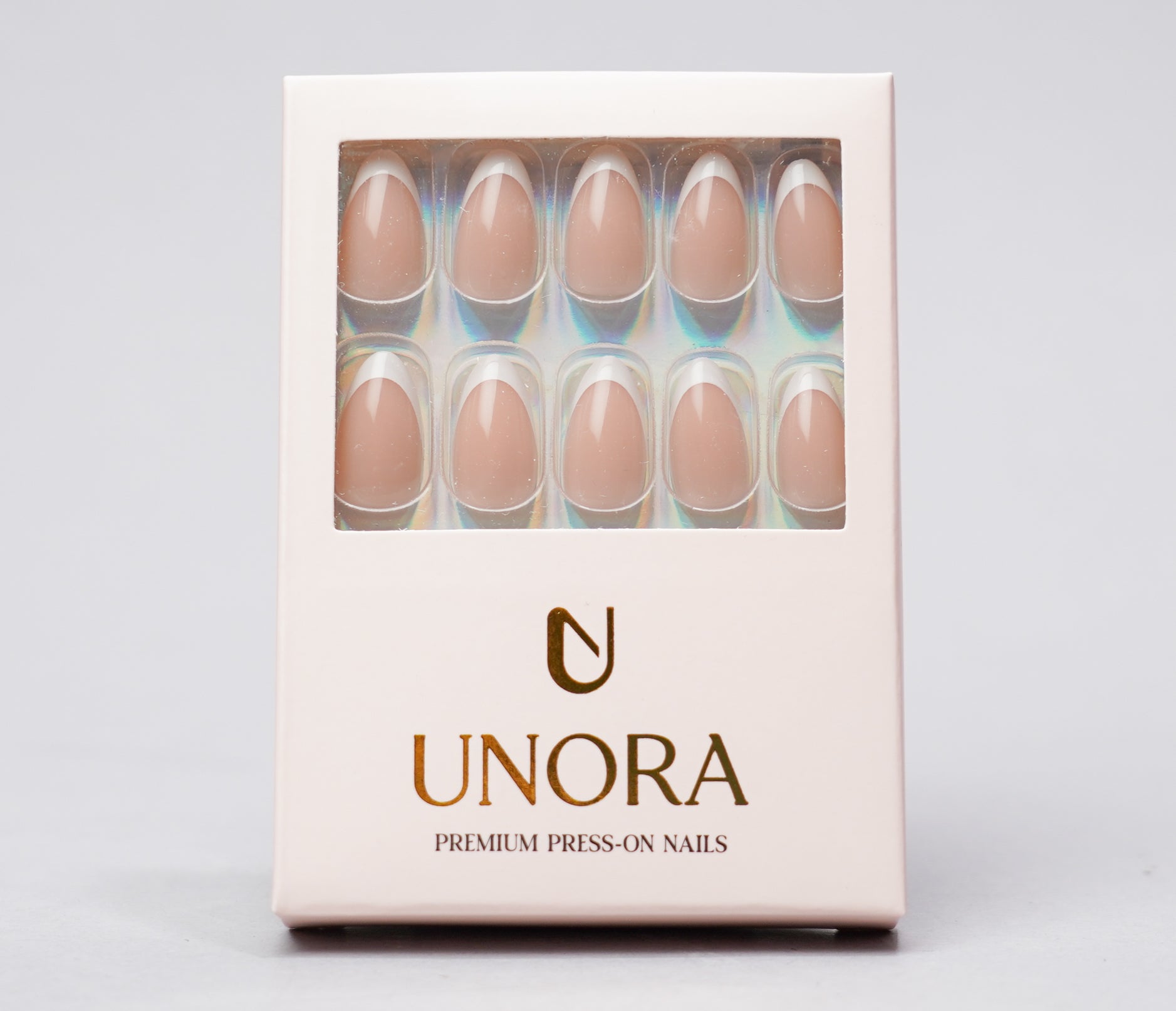 A box of UNORA press-on nails with a clear window showing ten nude beige nails, set against a light gray background.